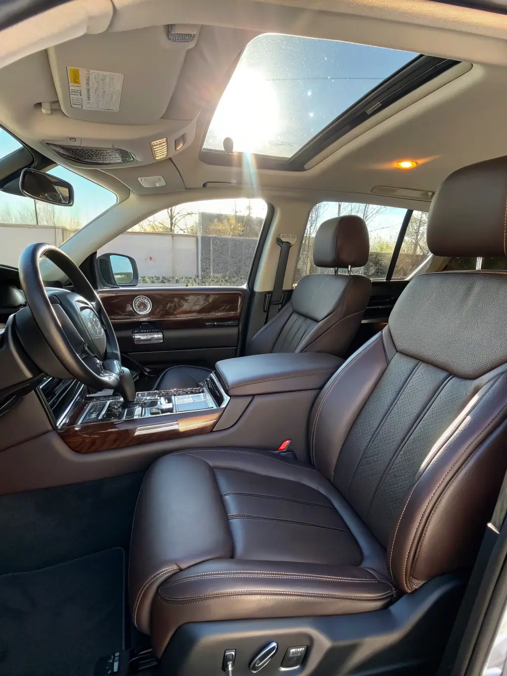 A technician vacuuming and cleaning the interior of a luxury vehicle, with focus on seats and dashboard, ensuring a spotless and fresh interior.